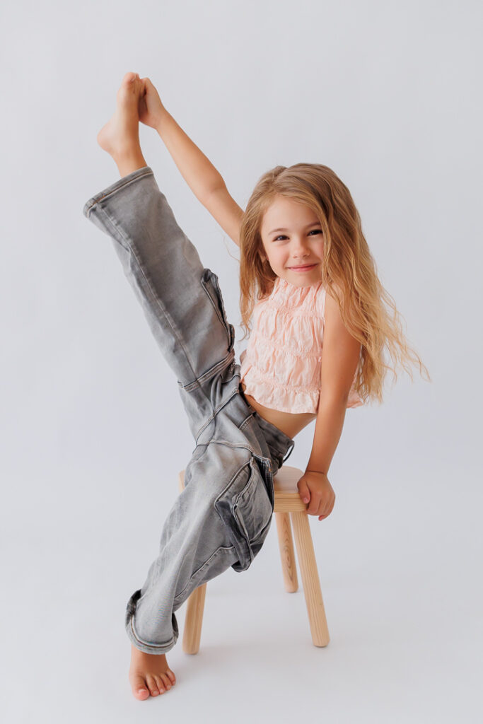 Mädchen streckt akrobatisch Bein und Arm in die Luft und lacht, Back-to-School-Mini-Session im Fotostudio Atelier 95 in Luxemburg