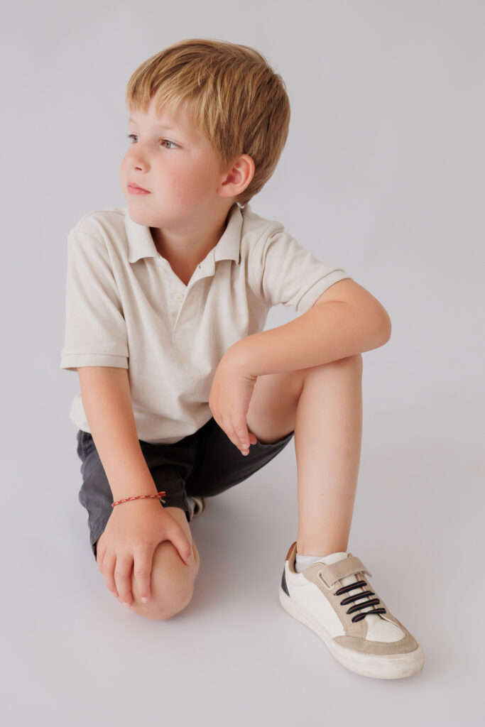 Junge macht verschmitzt eine Psst-Geste mit dem Finger vor dem Mund, Back-to-School-Mini-Session im Fotostudio Atelier 95 in Luxemburg